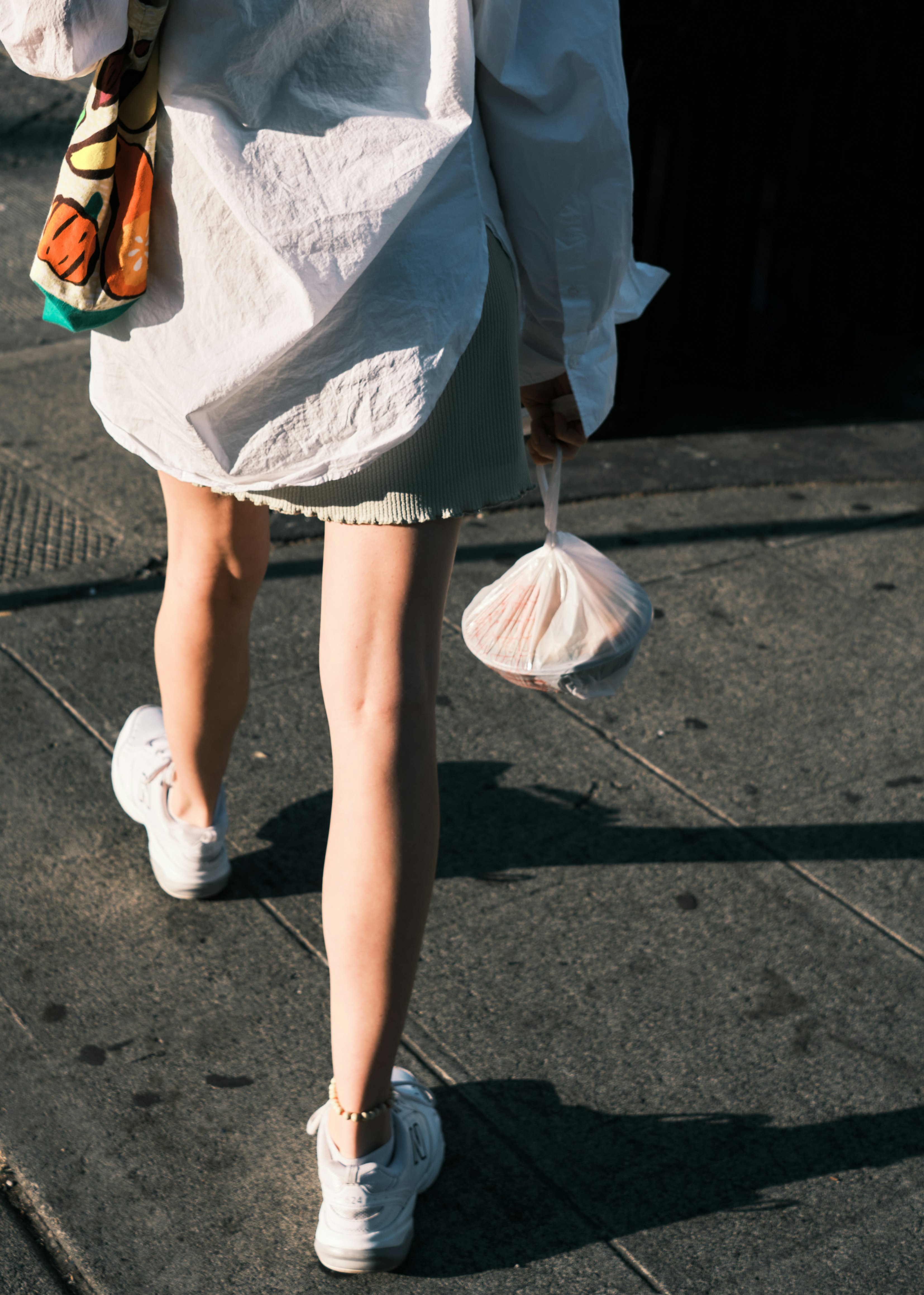 woman in white dress walking on sidewalk during daytime